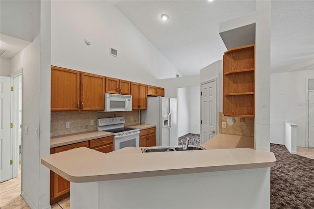 kitchen featuring decorative backsplash, sink, light tile patterned floors, kitchen peninsula, and white appliances