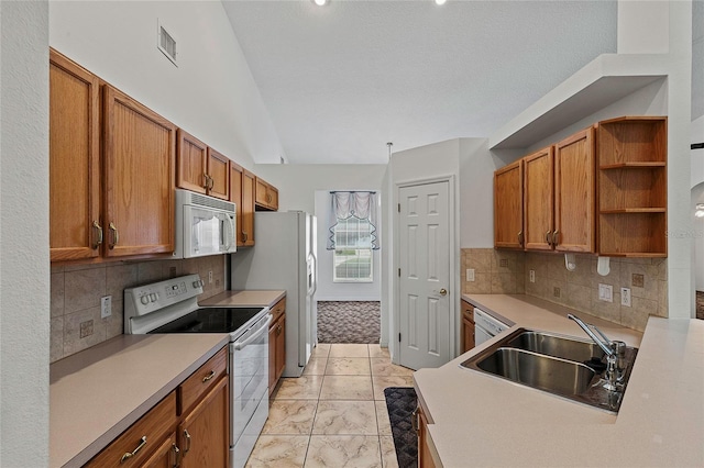 kitchen featuring sink, backsplash, white appliances, and light tile patterned floors