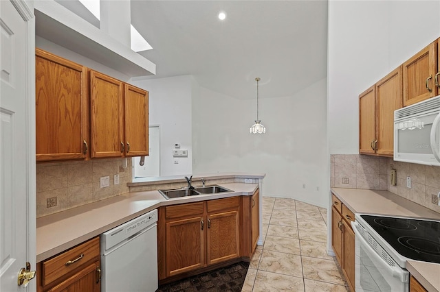 kitchen with sink, white appliances, tasteful backsplash, light tile patterned floors, and hanging light fixtures