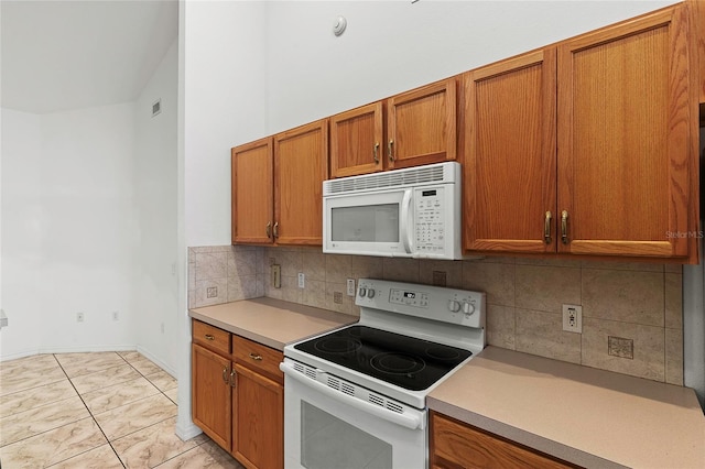 kitchen with white appliances, light tile patterned floors, and tasteful backsplash