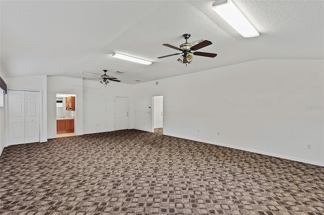 unfurnished living room featuring ceiling fan, vaulted ceiling, a textured ceiling, and carpet flooring