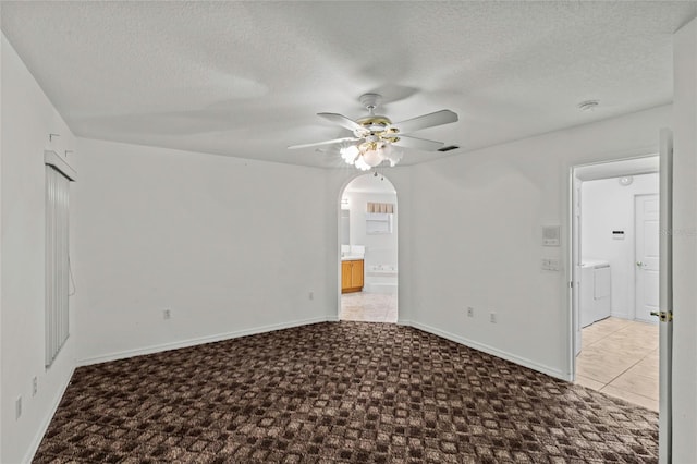 empty room with ceiling fan, washer and clothes dryer, a textured ceiling, and light tile patterned floors