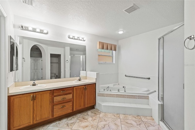 bathroom with tile patterned floors, double vanity, a textured ceiling, and plus walk in shower