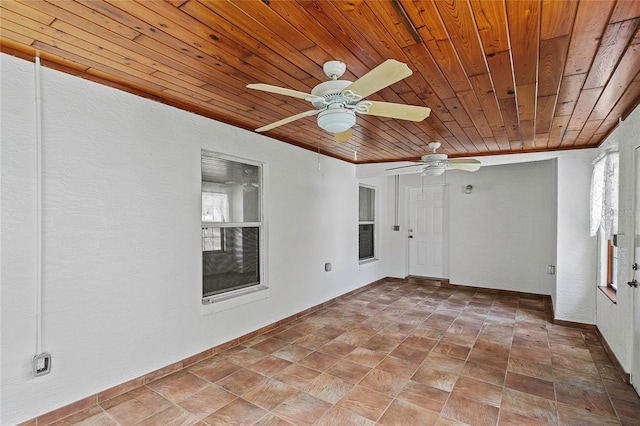 tiled empty room with a wealth of natural light, ceiling fan, and wood ceiling