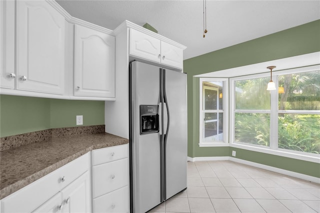 kitchen with light tile patterned floors, stainless steel refrigerator with ice dispenser, plenty of natural light, and white cabinets