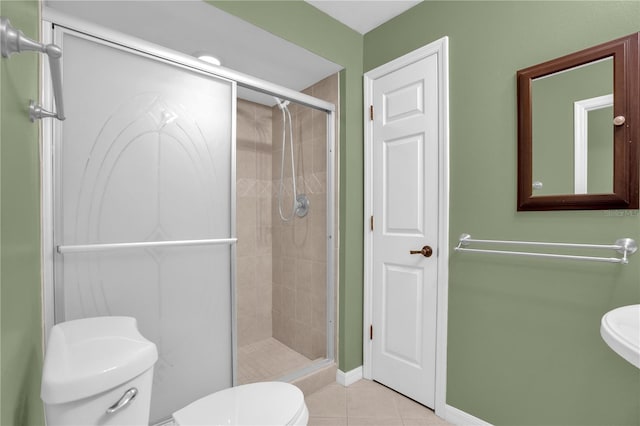 bathroom with tile patterned flooring, a shower with shower door, and toilet