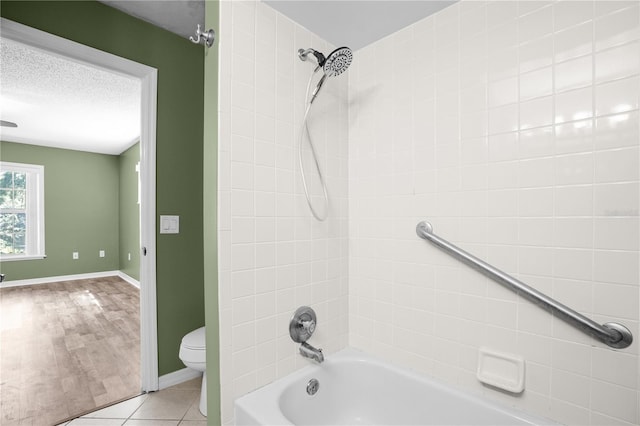 bathroom featuring a textured ceiling, toilet, tiled shower / bath, and wood-type flooring