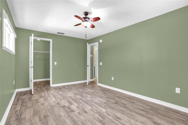 spare room with a textured ceiling, ceiling fan, and light wood-type flooring