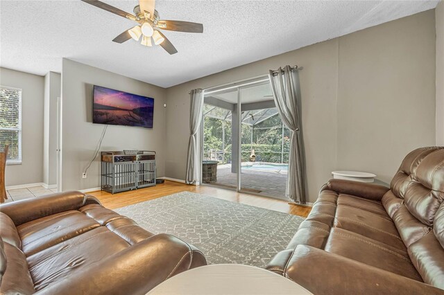 living room with a wealth of natural light, light hardwood / wood-style flooring, and ceiling fan