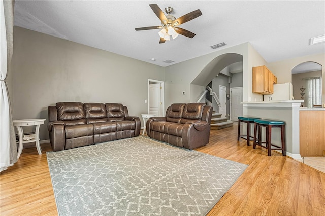 living room with ceiling fan, light hardwood / wood-style floors, and a textured ceiling