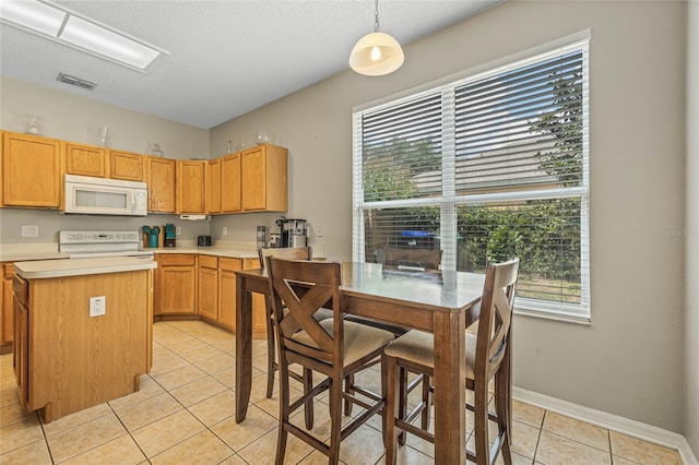 kitchen featuring a center island, light tile patterned floors, pendant lighting, and white appliances