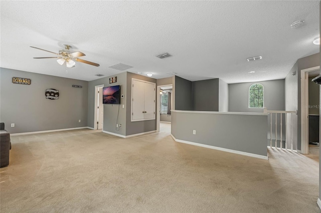 unfurnished living room featuring ceiling fan, light colored carpet, and a textured ceiling