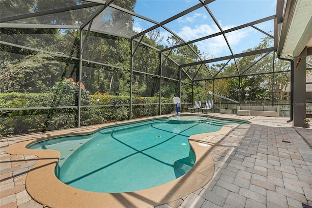 view of pool with glass enclosure and a patio area