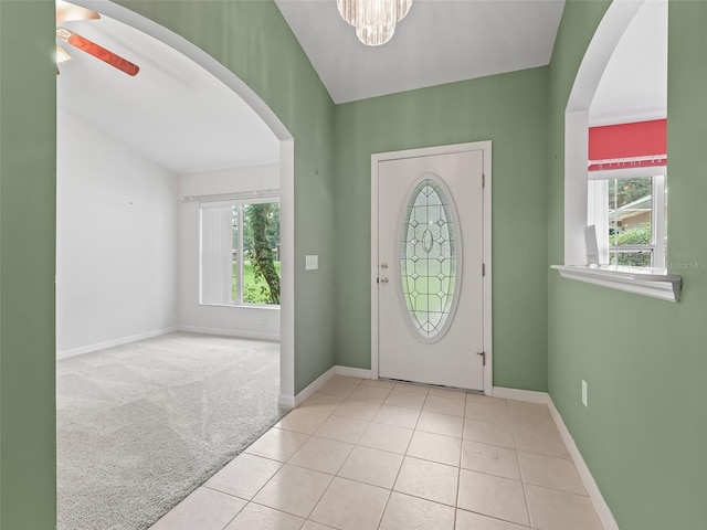 entrance foyer featuring light carpet, plenty of natural light, and ceiling fan with notable chandelier