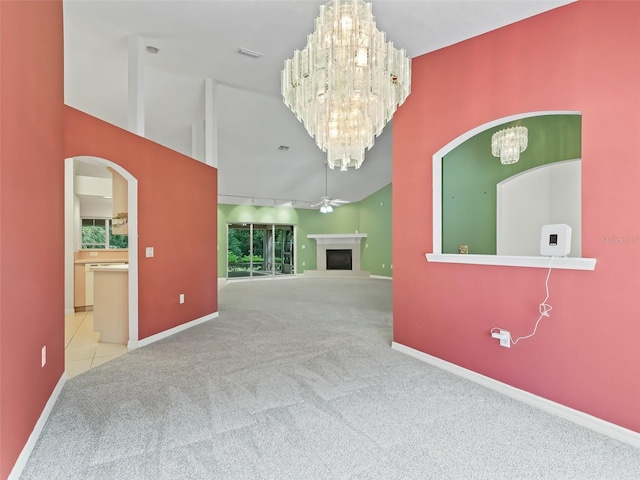 unfurnished living room with a high ceiling, ceiling fan with notable chandelier, rail lighting, and light colored carpet