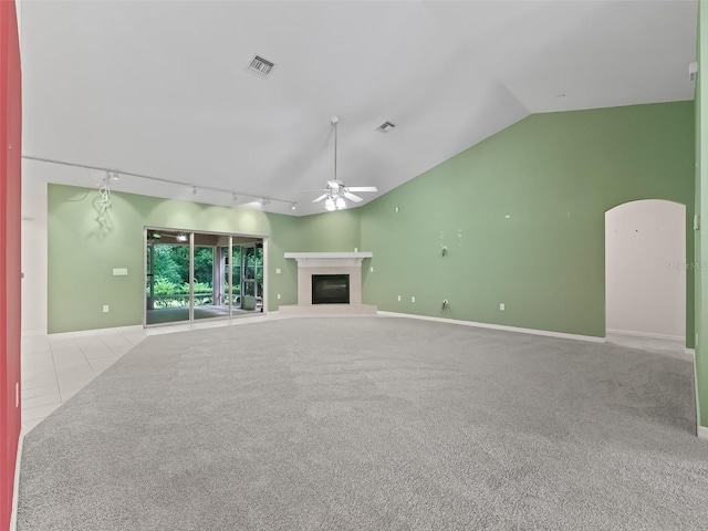 unfurnished living room featuring ceiling fan, vaulted ceiling, rail lighting, and light colored carpet