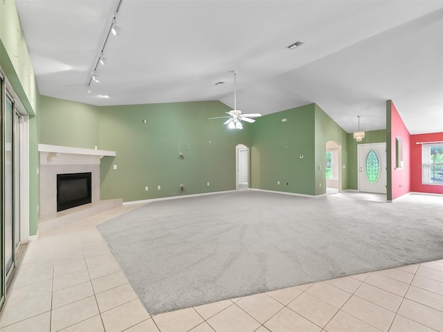 unfurnished living room with rail lighting, lofted ceiling, a high end fireplace, ceiling fan, and light tile patterned flooring