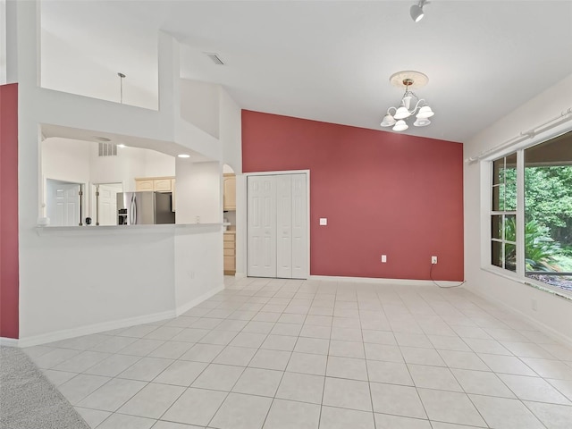 unfurnished room with light tile patterned floors, vaulted ceiling, and a notable chandelier