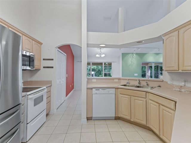 kitchen with plenty of natural light, appliances with stainless steel finishes, light tile patterned flooring, and a high ceiling