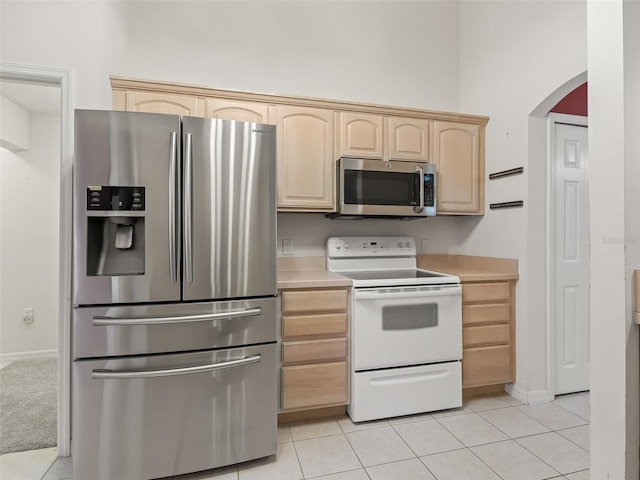 kitchen with light carpet, light brown cabinetry, and stainless steel appliances