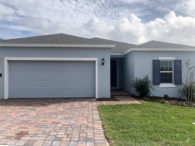 single story home featuring a garage and a front lawn