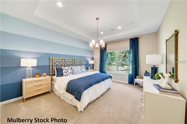 bedroom featuring a chandelier, light colored carpet, and a tray ceiling