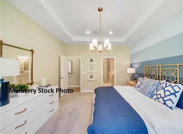 carpeted bedroom featuring a notable chandelier, ensuite bathroom, and a tray ceiling