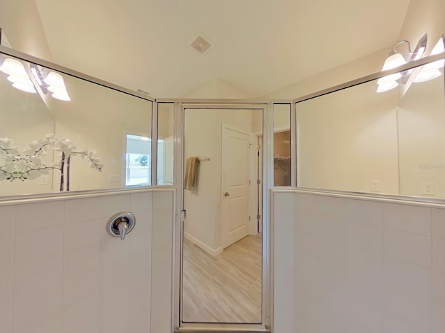 bathroom with tiled shower and wood-type flooring