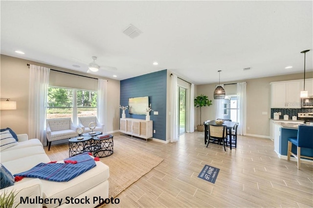 living room featuring ceiling fan and light hardwood / wood-style floors