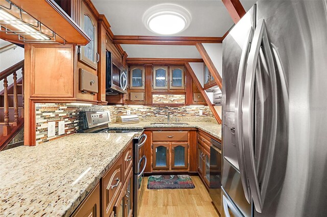 kitchen with stainless steel appliances, light hardwood / wood-style floors, decorative backsplash, sink, and light stone countertops