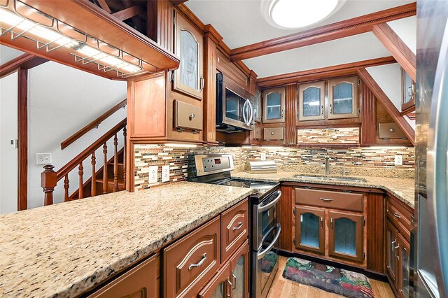 kitchen with stainless steel appliances, light stone countertops, tasteful backsplash, and light hardwood / wood-style flooring