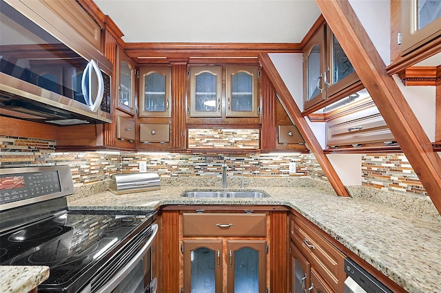 kitchen with appliances with stainless steel finishes, light stone countertops, sink, and tasteful backsplash