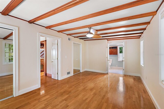 empty room featuring ceiling fan, light hardwood / wood-style floors, and beamed ceiling