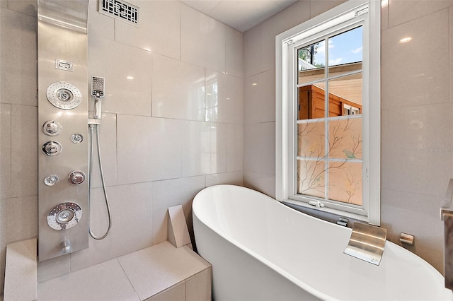 bathroom with a tub and tile walls