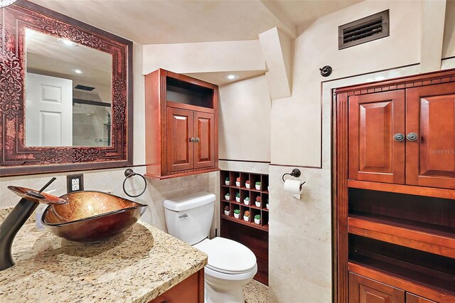 bathroom featuring tile walls, vanity, and toilet