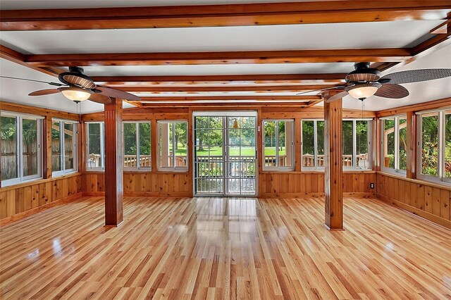 unfurnished sunroom featuring ceiling fan, beamed ceiling, and a healthy amount of sunlight