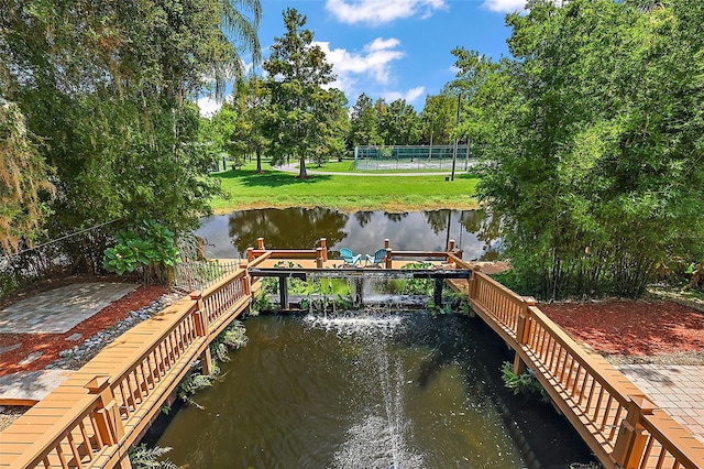 view of dock with a water view and a yard