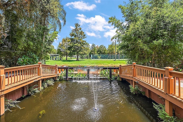 view of dock featuring a lawn and a deck with water view