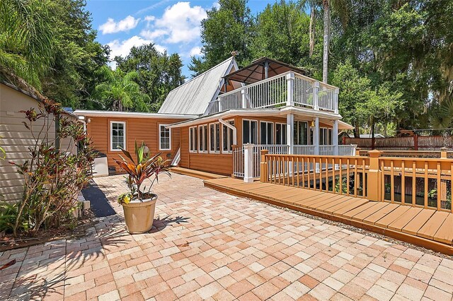 rear view of house with a wooden deck and a patio area