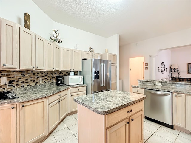 kitchen featuring ornate columns, stainless steel appliances, tasteful backsplash, and light tile patterned flooring