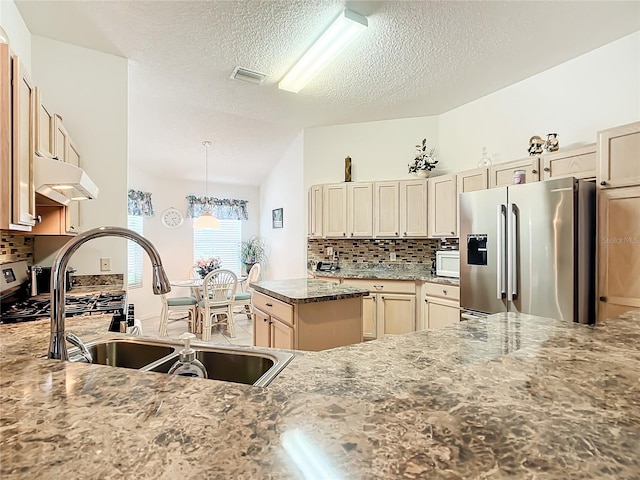 kitchen featuring a textured ceiling, stainless steel fridge with ice dispenser, hanging light fixtures, sink, and dark stone counters