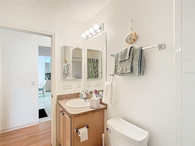 bathroom with a textured ceiling, vanity, toilet, and hardwood / wood-style flooring