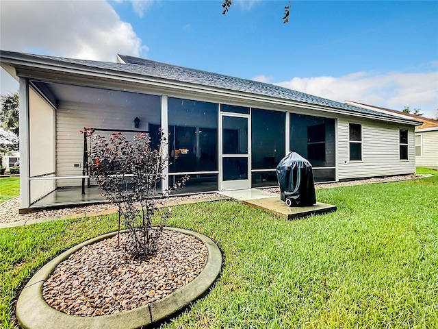 rear view of house featuring a sunroom, a patio area, and a lawn