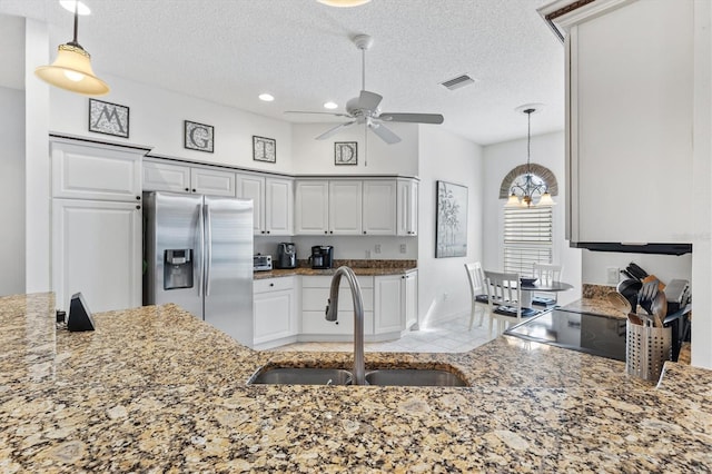 kitchen with decorative light fixtures, stainless steel refrigerator with ice dispenser, sink, tile patterned floors, and a textured ceiling