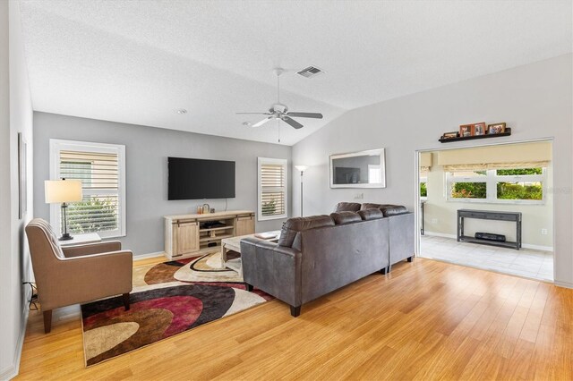 living room with light wood-type flooring, vaulted ceiling, and ceiling fan