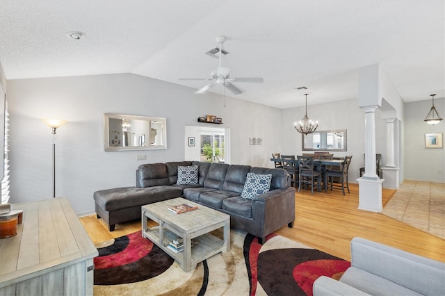 living room featuring ceiling fan with notable chandelier, vaulted ceiling, light hardwood / wood-style floors, and ornate columns