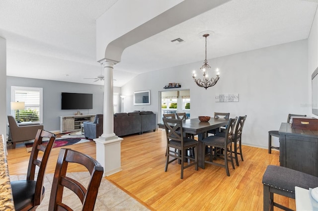 dining area featuring ornate columns, vaulted ceiling, ceiling fan with notable chandelier, and light wood-type flooring