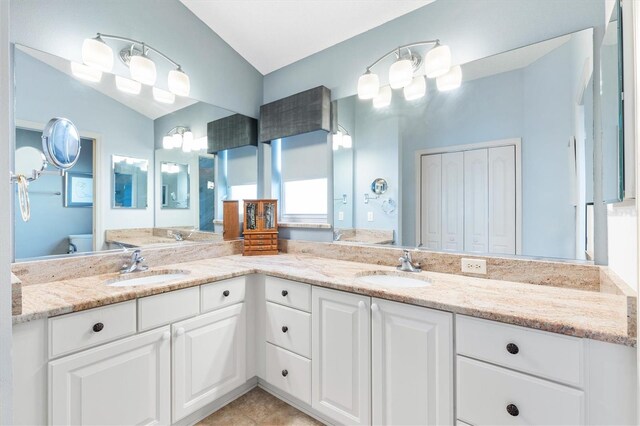 bathroom featuring tile patterned flooring, toilet, vaulted ceiling, and vanity