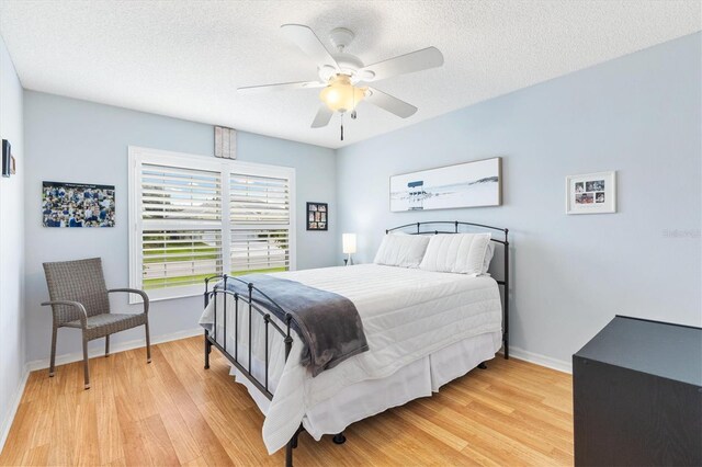 bedroom with ceiling fan, a textured ceiling, and light hardwood / wood-style flooring