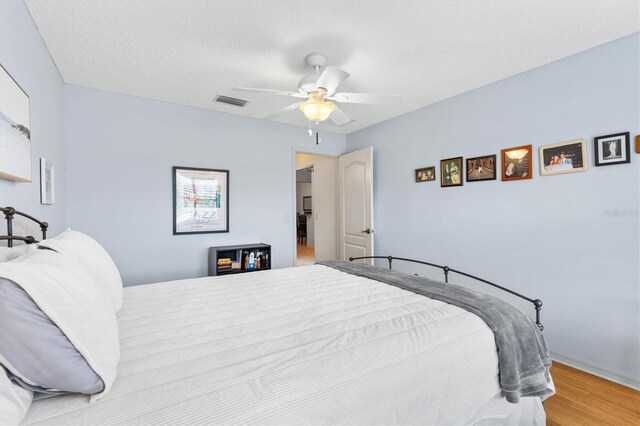 bedroom featuring a textured ceiling, ceiling fan, and light wood-type flooring